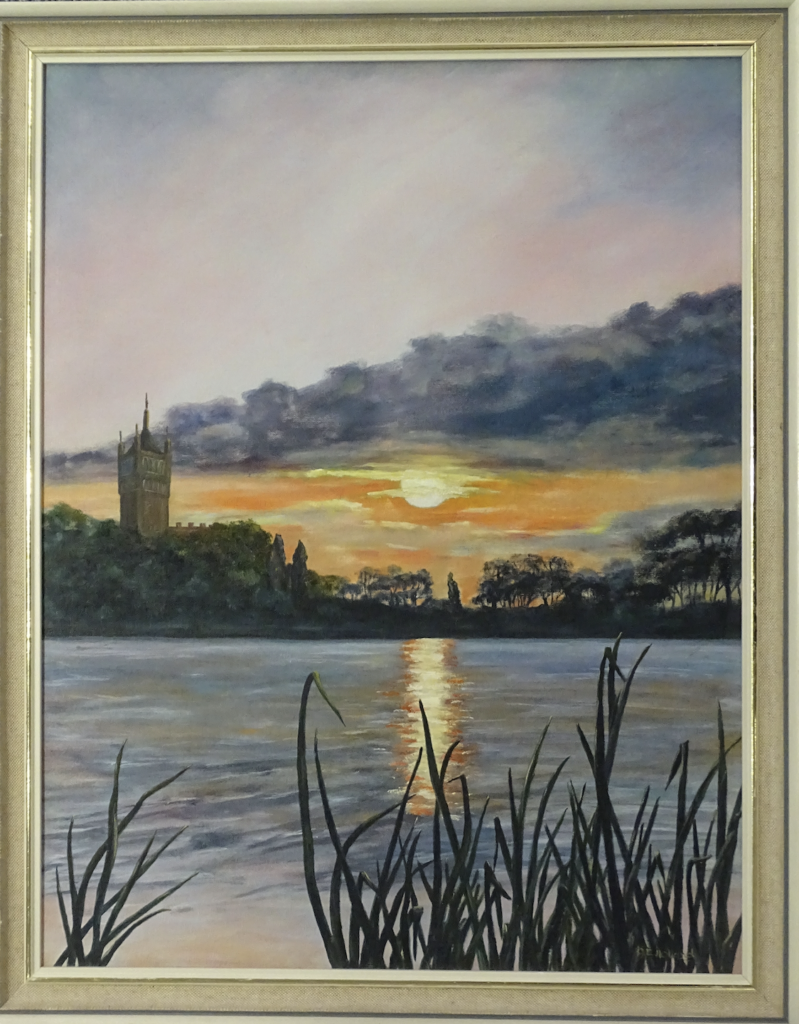 beige wooden framed acrylic painting of sunset at lake Thorpe. Foreground of painting shows lake with yellow and orange reflection. There are dark green weeds in the foreground. In the background, dense flora expands from right to left, with the tower from Holloway Sanatorium peeking on the left side. The sky at the top of the painting is divided in three parts horizontally: orange and yellow sunset just above the landscape, a dark blue and grey cloud above the sun, and a pink and light blue sky at the very top