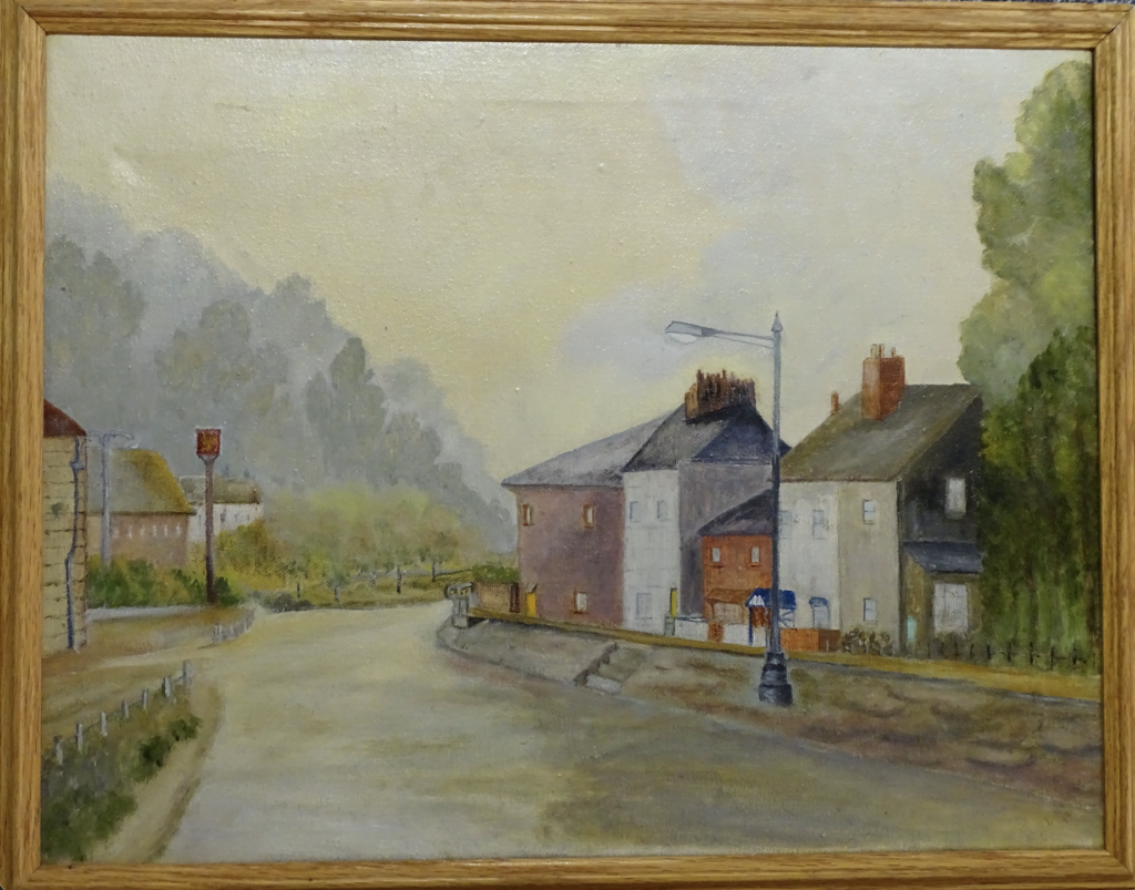 View of burgundy, red, white coloured cottages on the right side of the oil painting. There is a road in the middle of the painting, with a street lamp on the right side. On the left, a partial view with a pub with a tall pub sign to the right of it. View of hills with tall trees in the background. Sky in yellow, white and blue tones